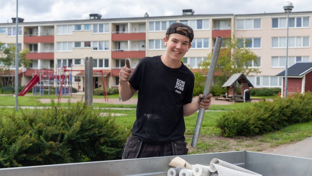Glad sommarjobbare vid släpvagn.