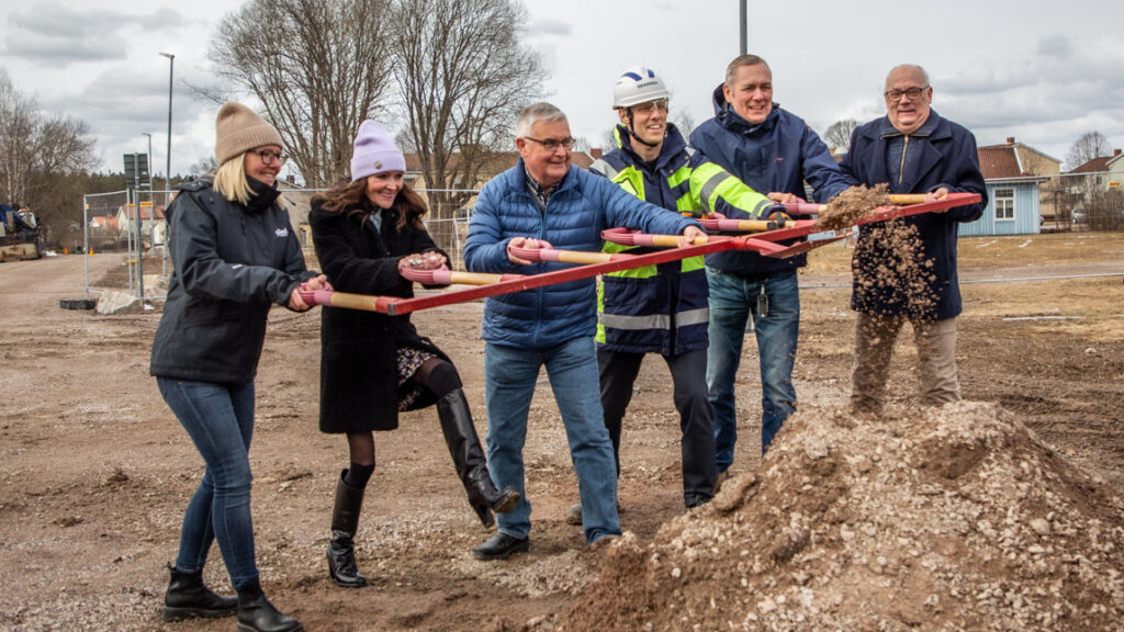 En grupp människor som håller fast vid en stor första-spadtaget-anordning.