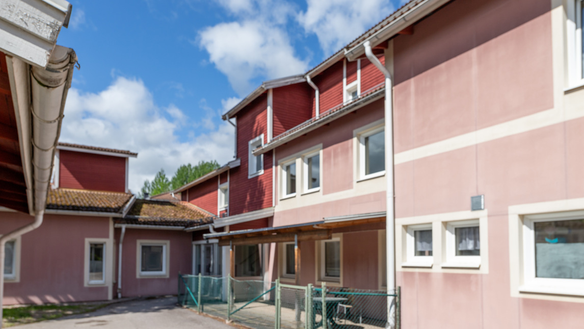 Ett rosa/rött hyreshus med många fönster.