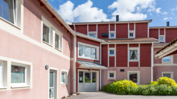 Ett rosa/rött hyreshus med många fönster.