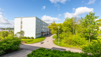 Ljusgrönt hyreshus med grönskade innergård.