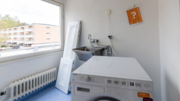 Tvättmaskin och tvättställ i ett våtrumsutrymme.