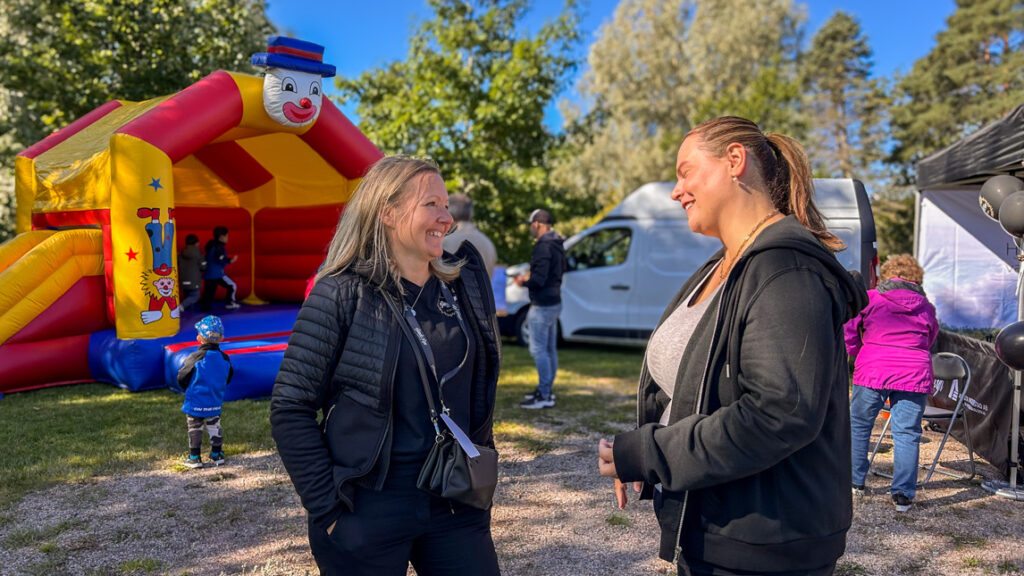 Två glada kvinnor framför en hoppborg.