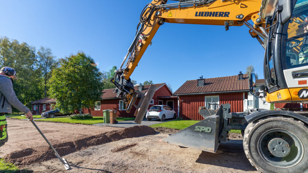 En man som står bredvid en traktor på en grusväg.