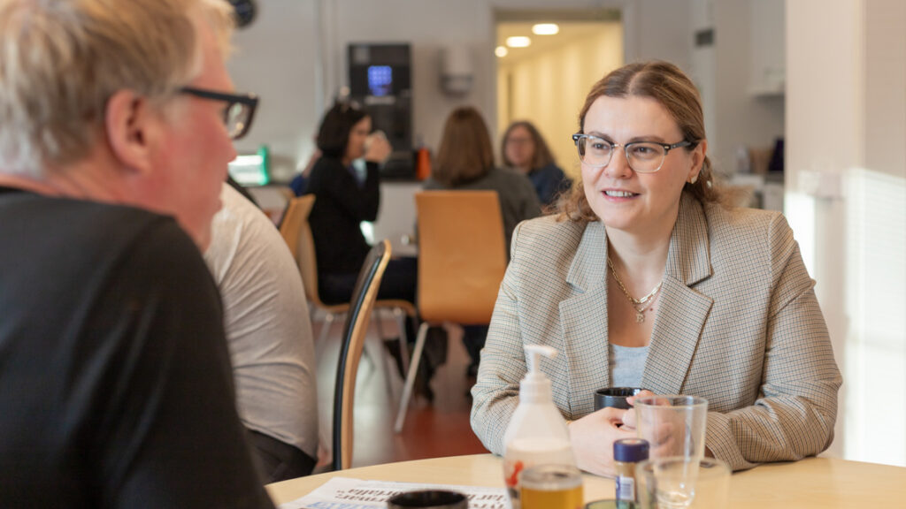 En kvinna sitter vid ett bord och pratar med en man.