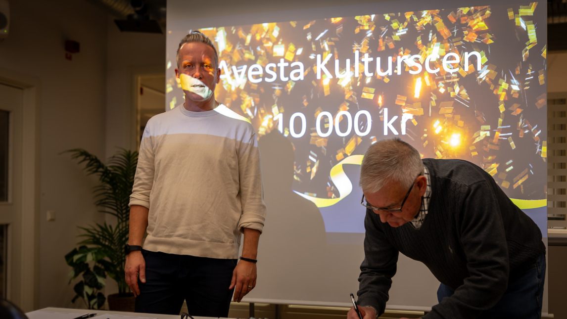 Två personer står vid en projektorduk.