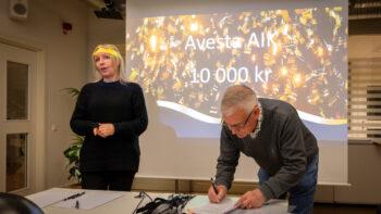 Två personer står vid en projektorduk.