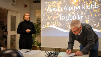 Två personer står vid en projektorduk.