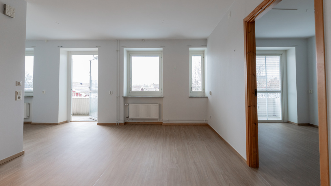 Ett tomt rum med vita väggar och trägolv.