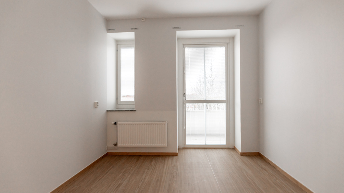 Ett tomt rum med vita väggar och trägolv.