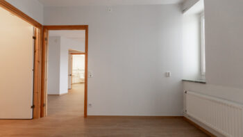 Ett tomt rum med vita väggar och trägolv.