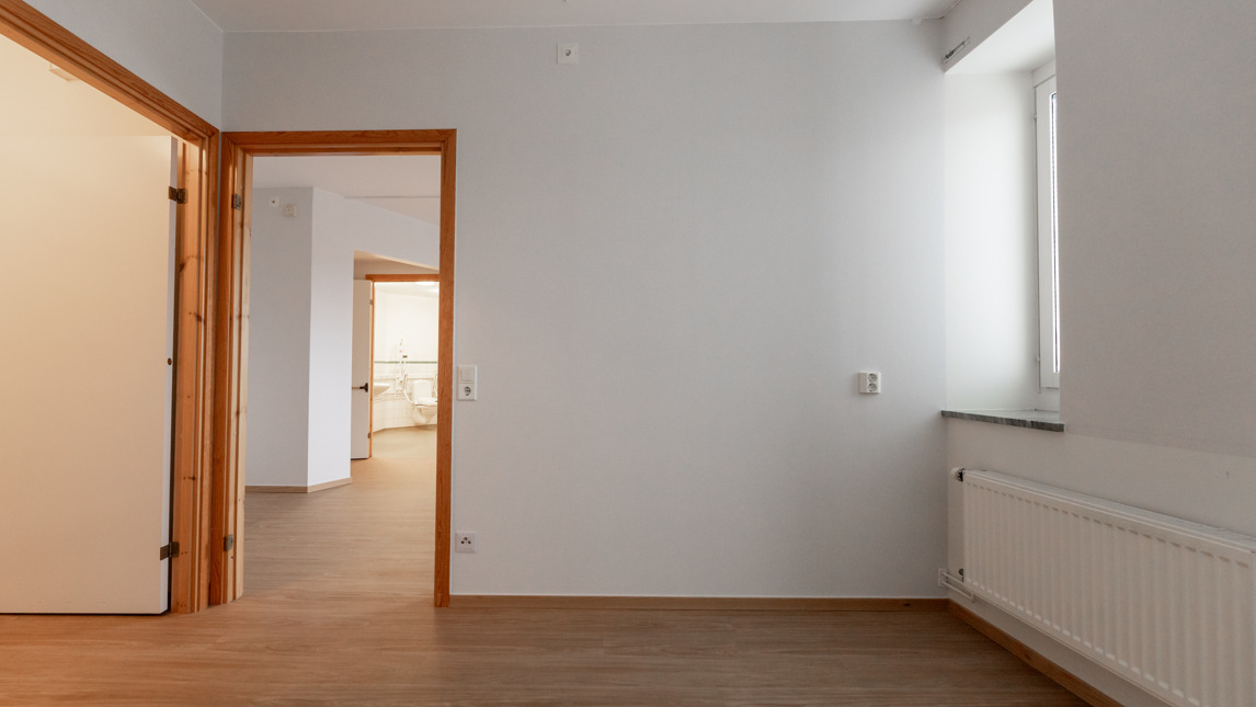 Ett tomt rum med vita väggar och trägolv.