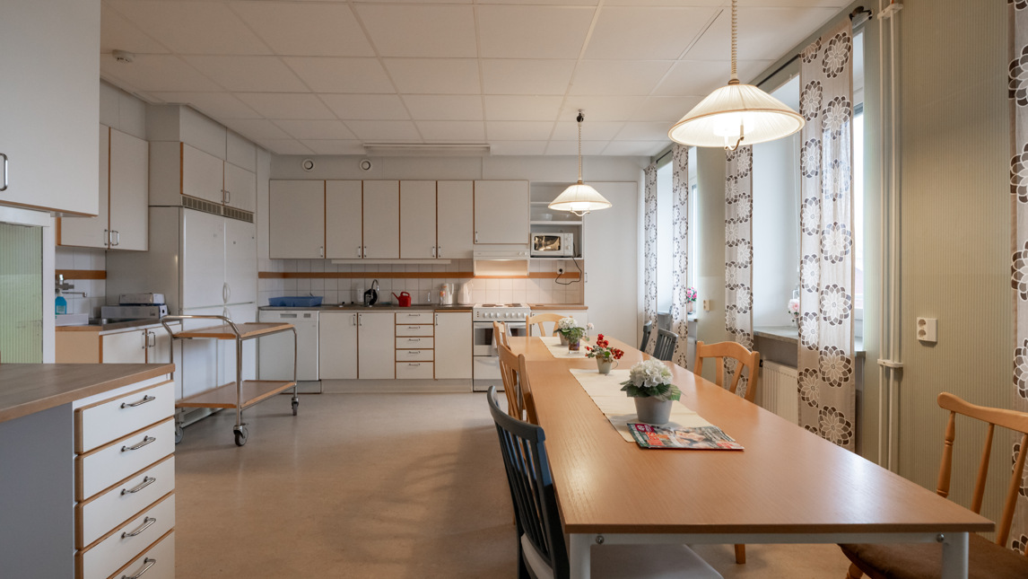 Ett stort kök med ett långt bord och stolar.