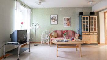 Möblerad vardagsrum med soffa, soffbord, vitrinskåp och TV.