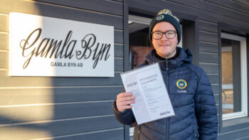 En man i blå jacka håller upp ett papper.