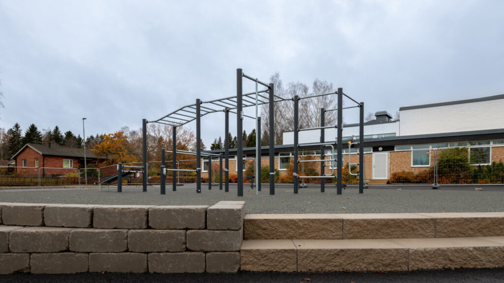 En park med en lekplats och en byggnad i bakgrunden.