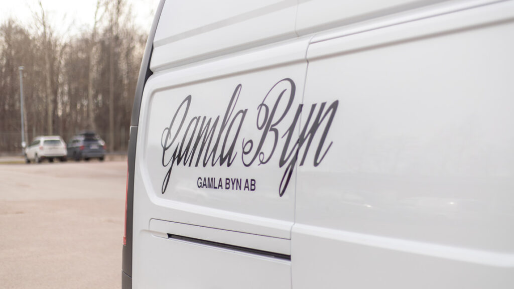 Vit servicebil med Gamla Byn AB logotyp på sidan.