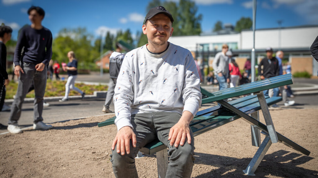 En man sitter på en specialdesignad parkbänk.